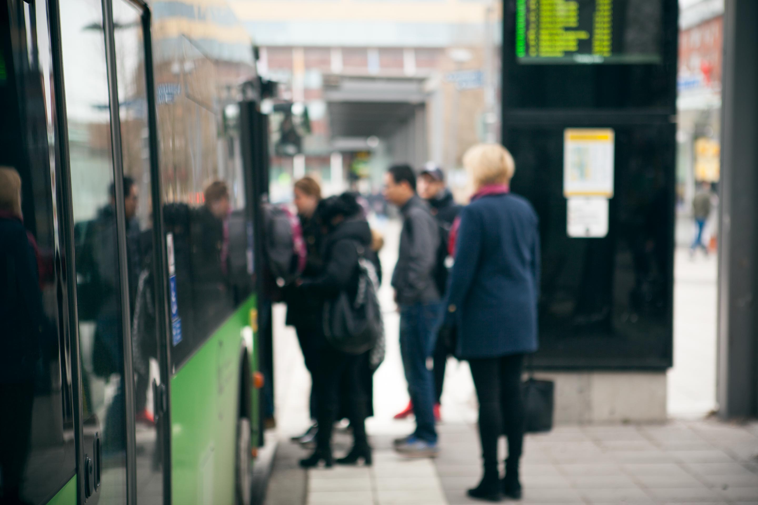 Miljöbild diffusa personer på stadsbusshållplats