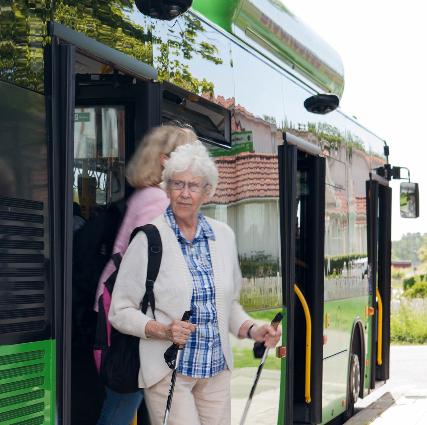 Äldre dam med gåstavar går av stadsbuss